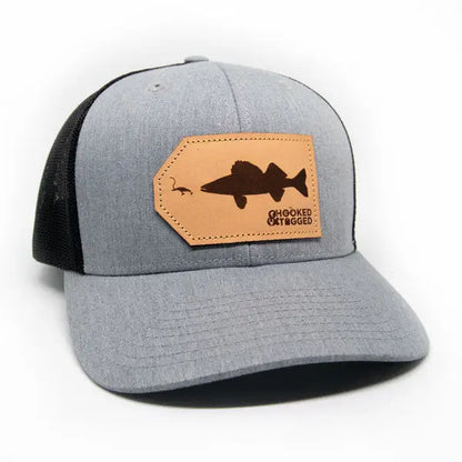 Gray and black cap with a leather patch featuring a fish design on a white background