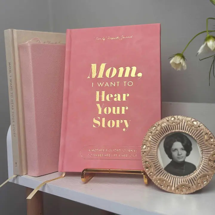 Pink book titled 'Mom, I Want to Hear Your Story' on a shelf with a photo frame.