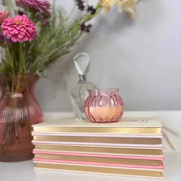 Stack of books with a pink candle and flowers in the background